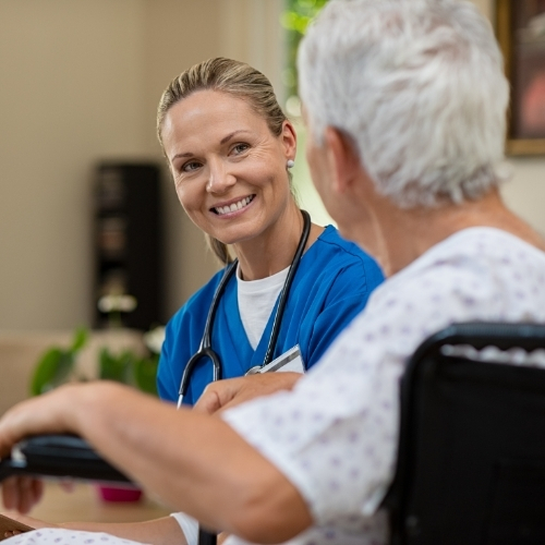 A nurse providing in-home care to a patient, illustrating community-based health services and neighbourhood-level care delivery
