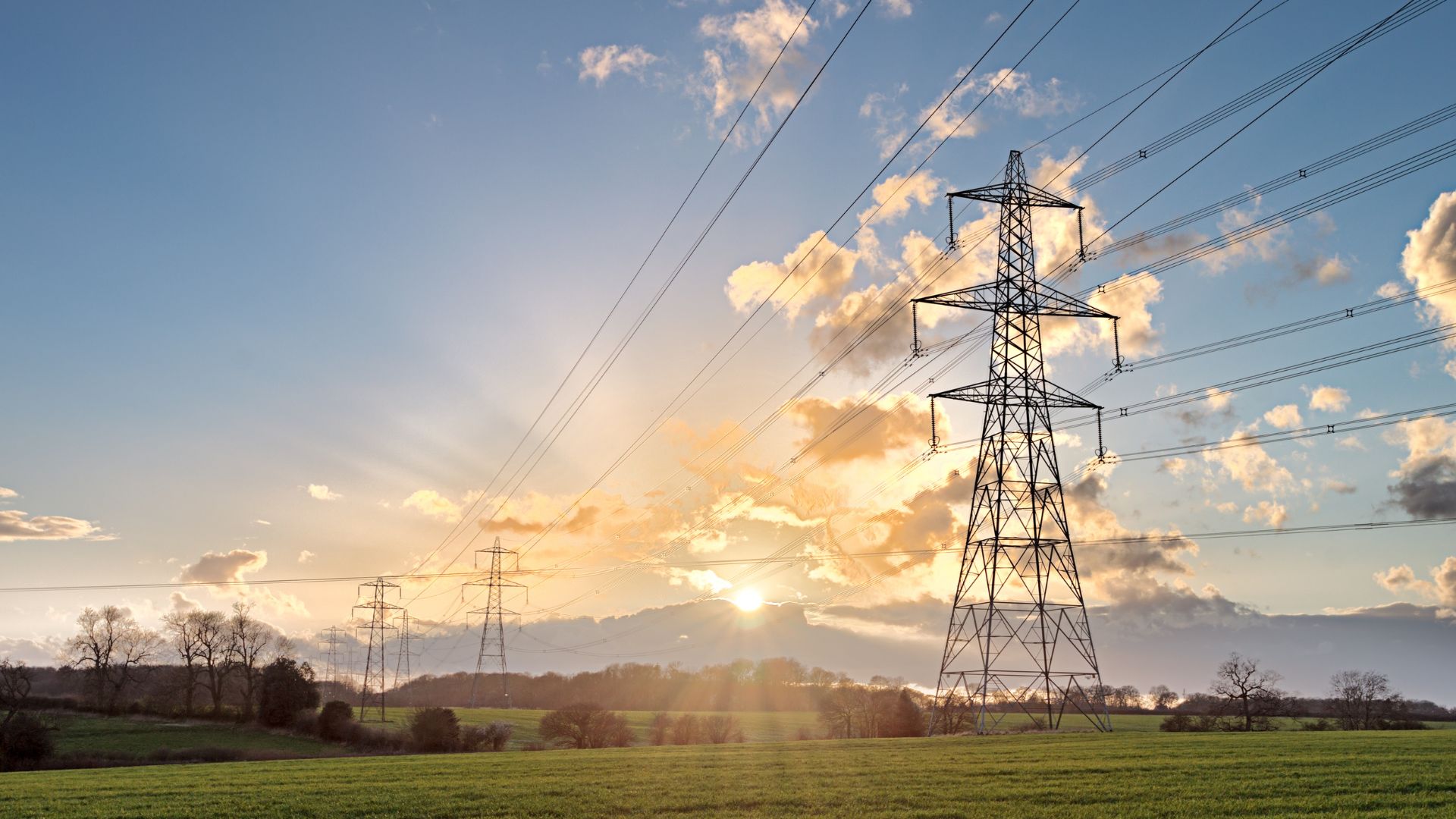 UK electricity transmission pylons across a rural landscape, representing National Grid infrastructure and carbon reduction in energy networks.