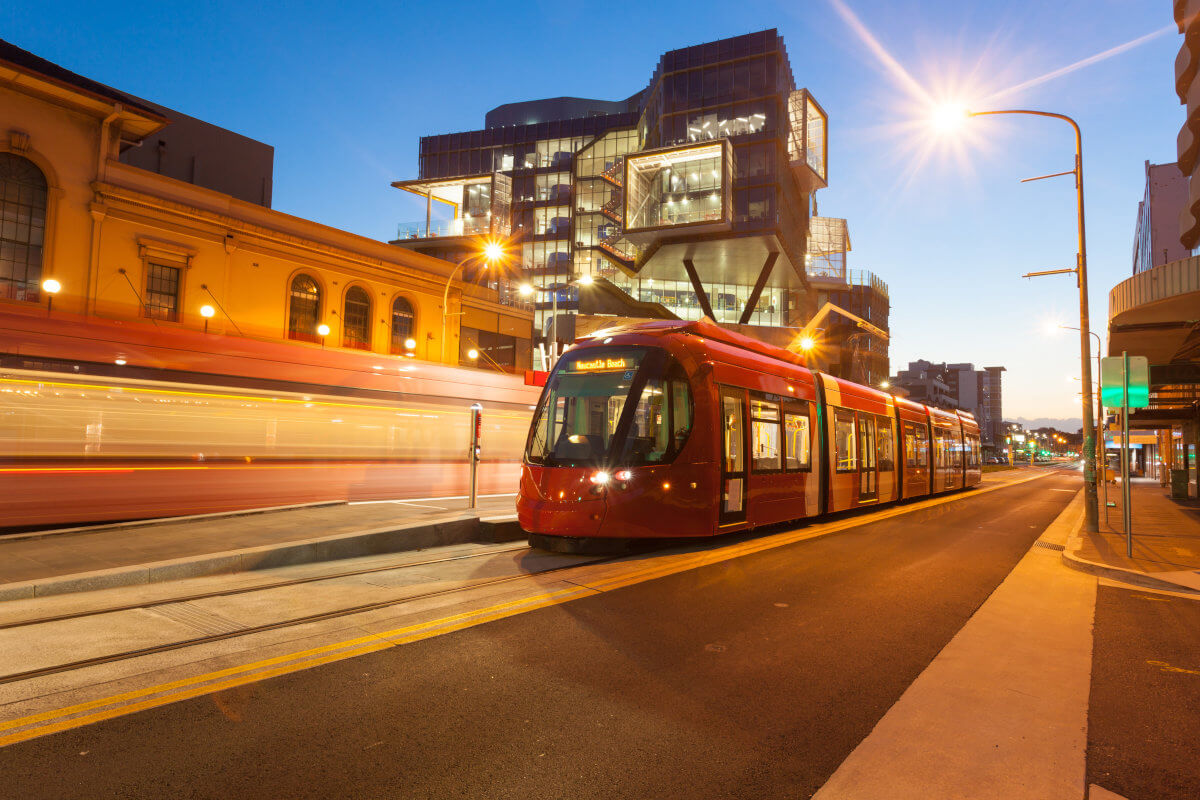 Red tram at a stop during twilight in Newcastle, Australia.