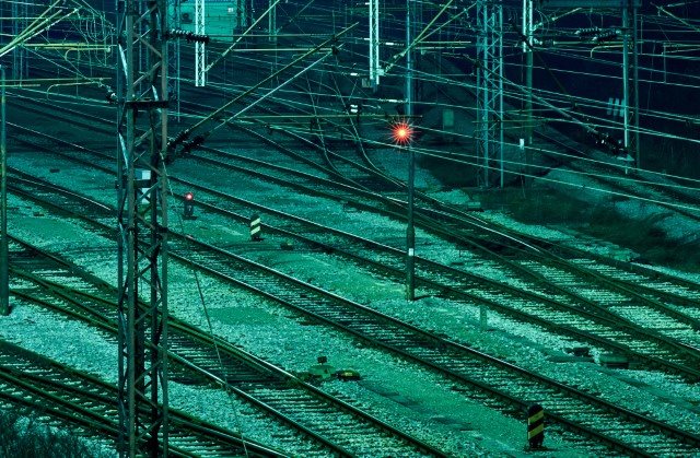 Single red light over a junction of railway tracks.