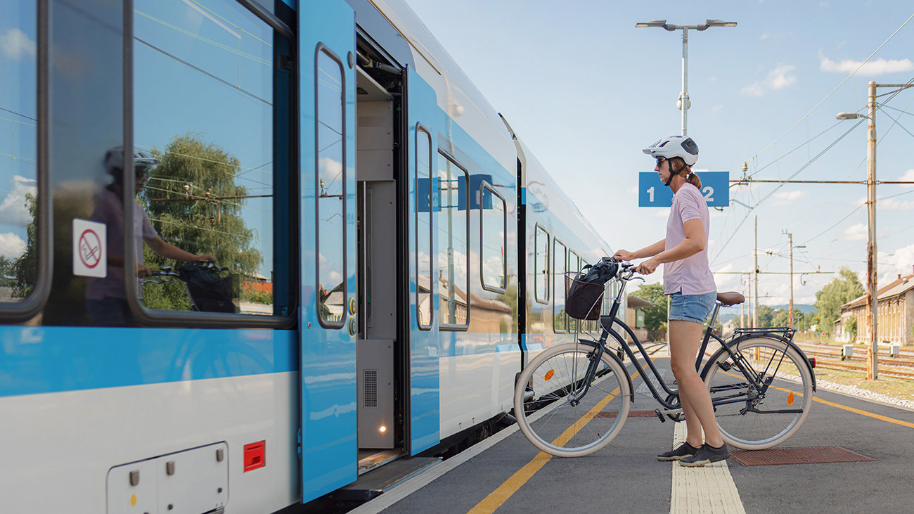 Woman with a bicycle boarding a train.