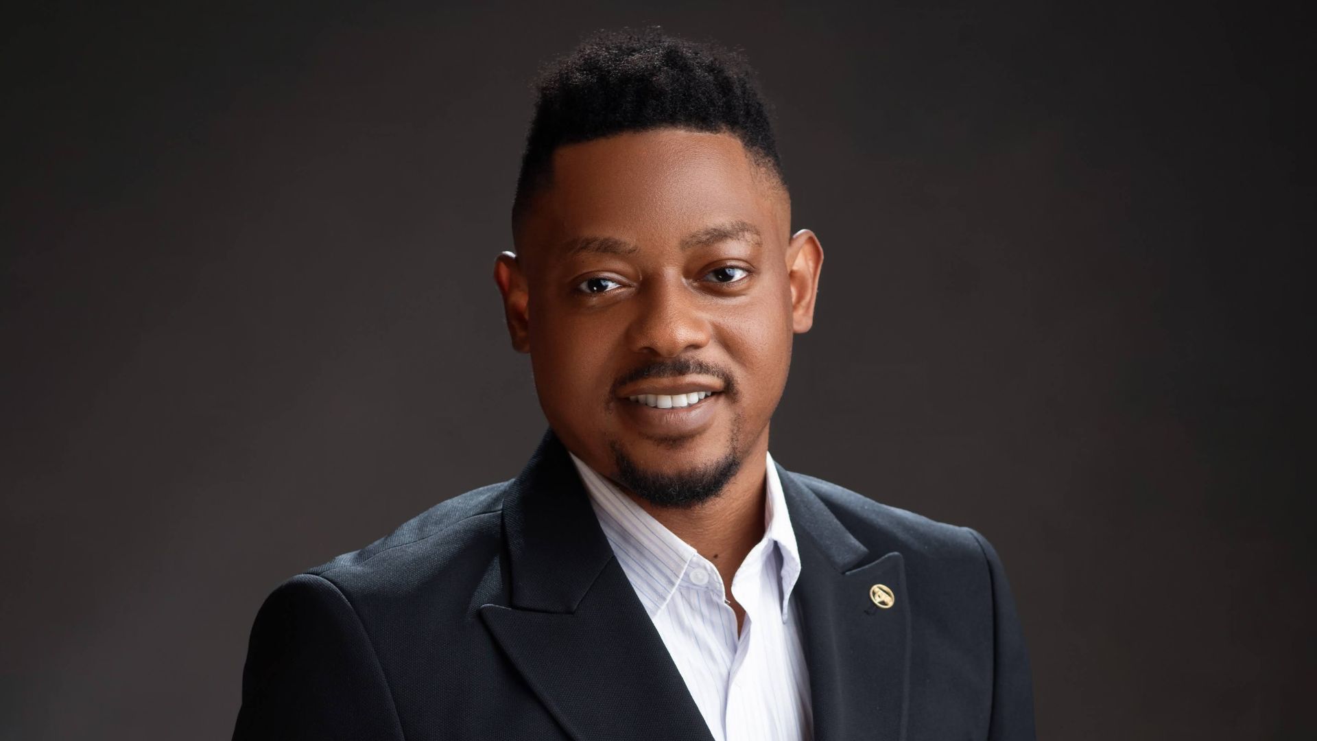 Professional headshot of Kelo Uchendu, wearing a dark suit jacket