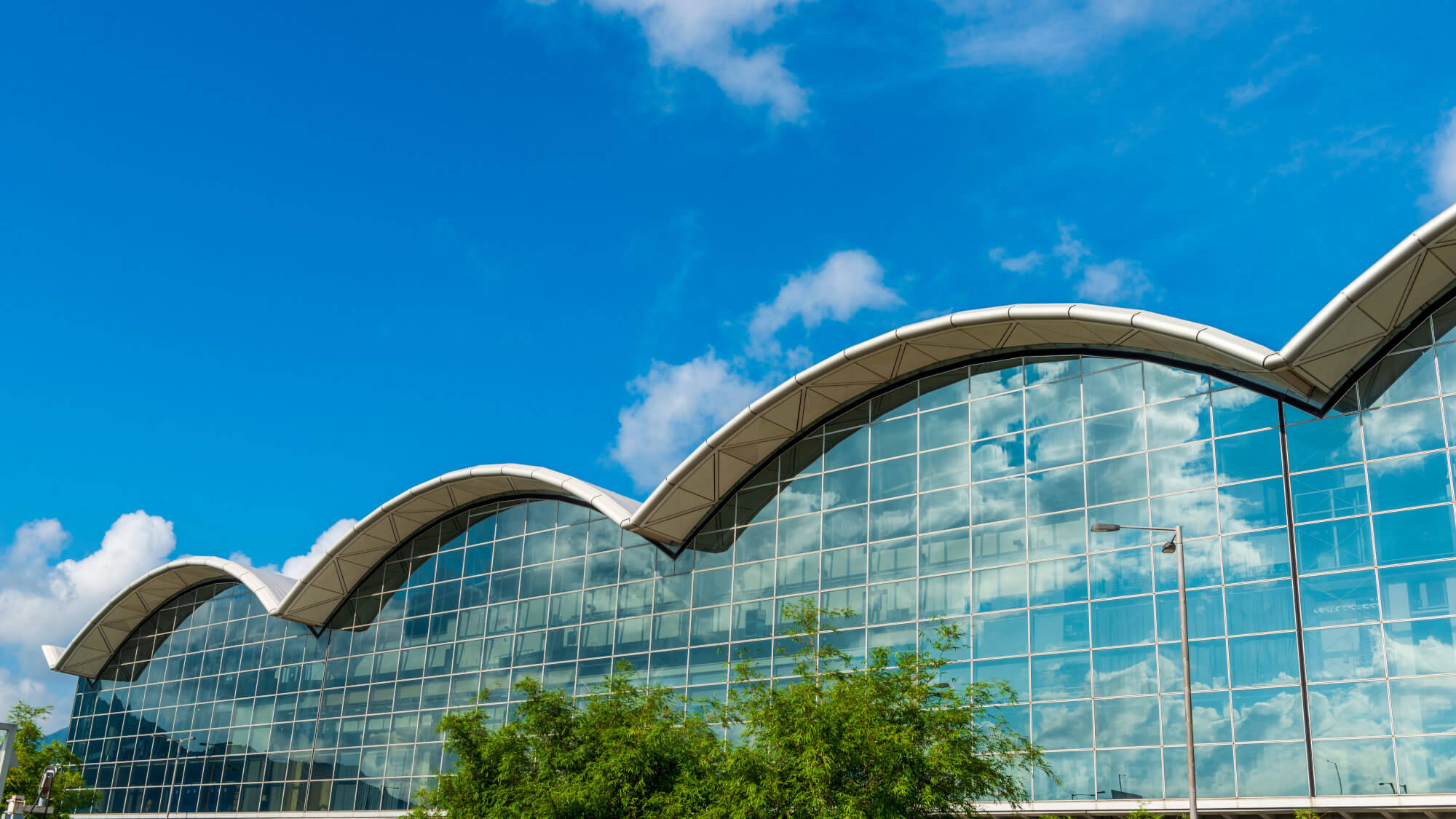 Hong Kong International airport facade under a blue sky.