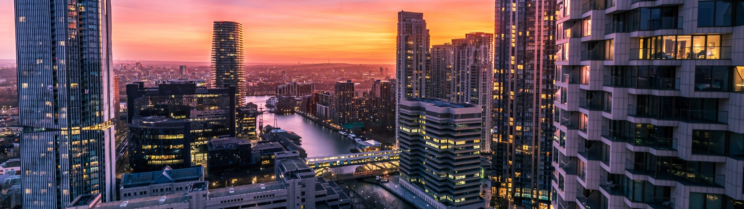 Sunset over a striking city skyline of glass-fronted offices and towering skyscrapers, symbolising architectural excellence and purposeful development.