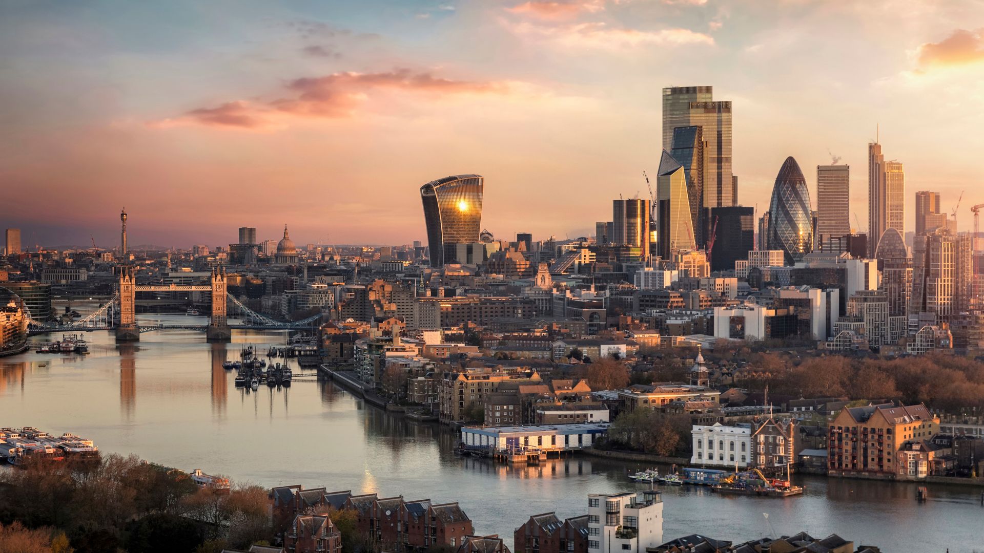 A wide view of London’s skyline at sunset, showing the River Thames, Tower Bridge, and the City of London’s cluster of modern skyscrapers. The image highlights key infrastructure and development areas relevant to the new London Infrastructure Framework.

