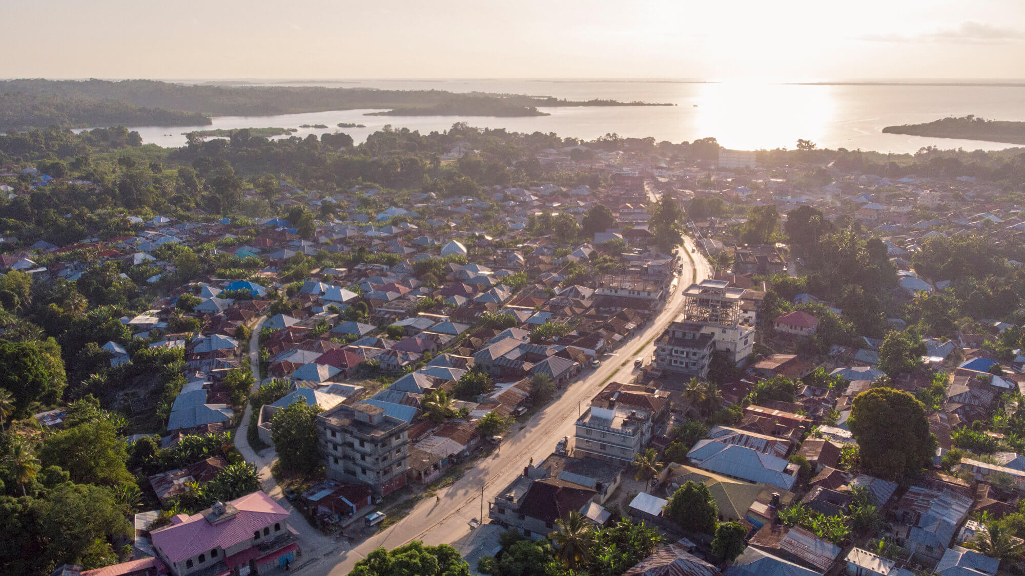 City neighbourhood with sea and sun in background.