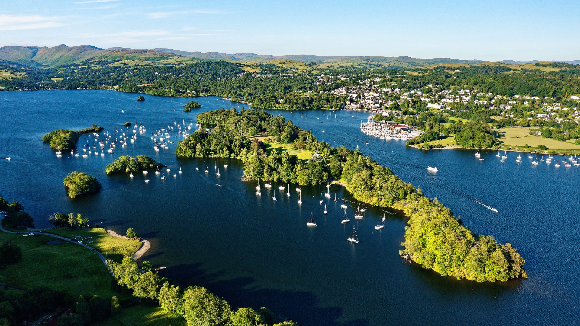 Aerial view of Windermere in the Lake District, showing the lake, surrounding green landscape and nearby town, illustrating the area set for Mott MacDonald’s transformational upgrade of Windermere rail station and transport hub.