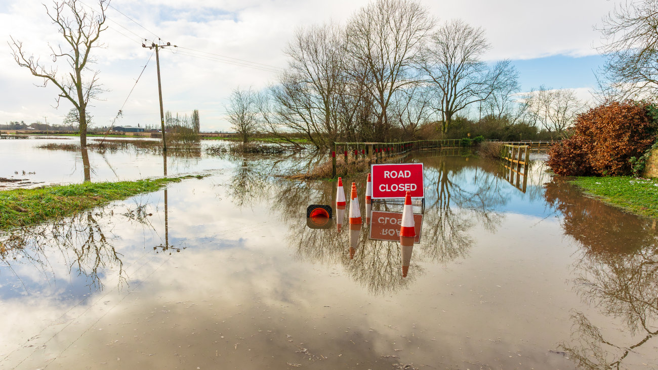 A flooded road with warning cones and sign.
