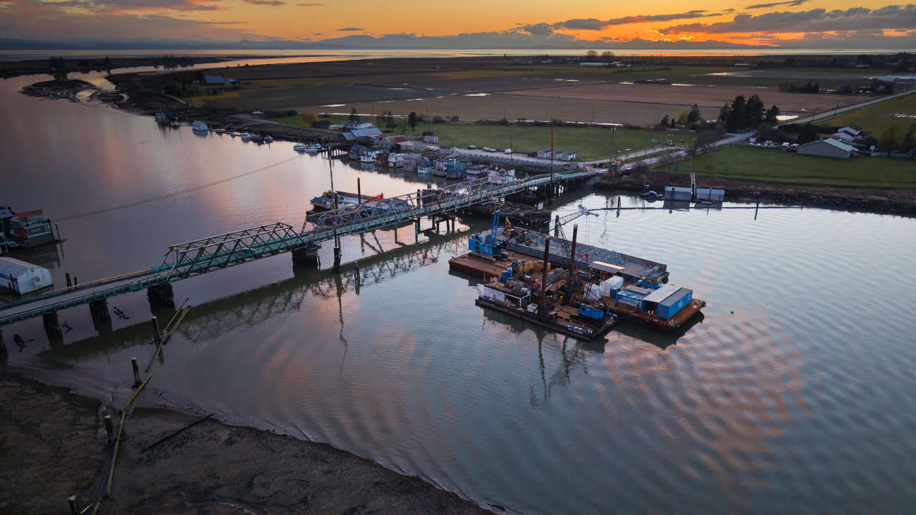 A bridge spanning a river with fields in the background.