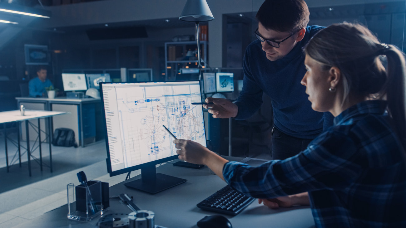 Engineers discussing a design on a computer screen.