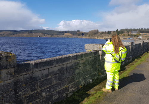 Construction working surveying the landscape through binoculars. 