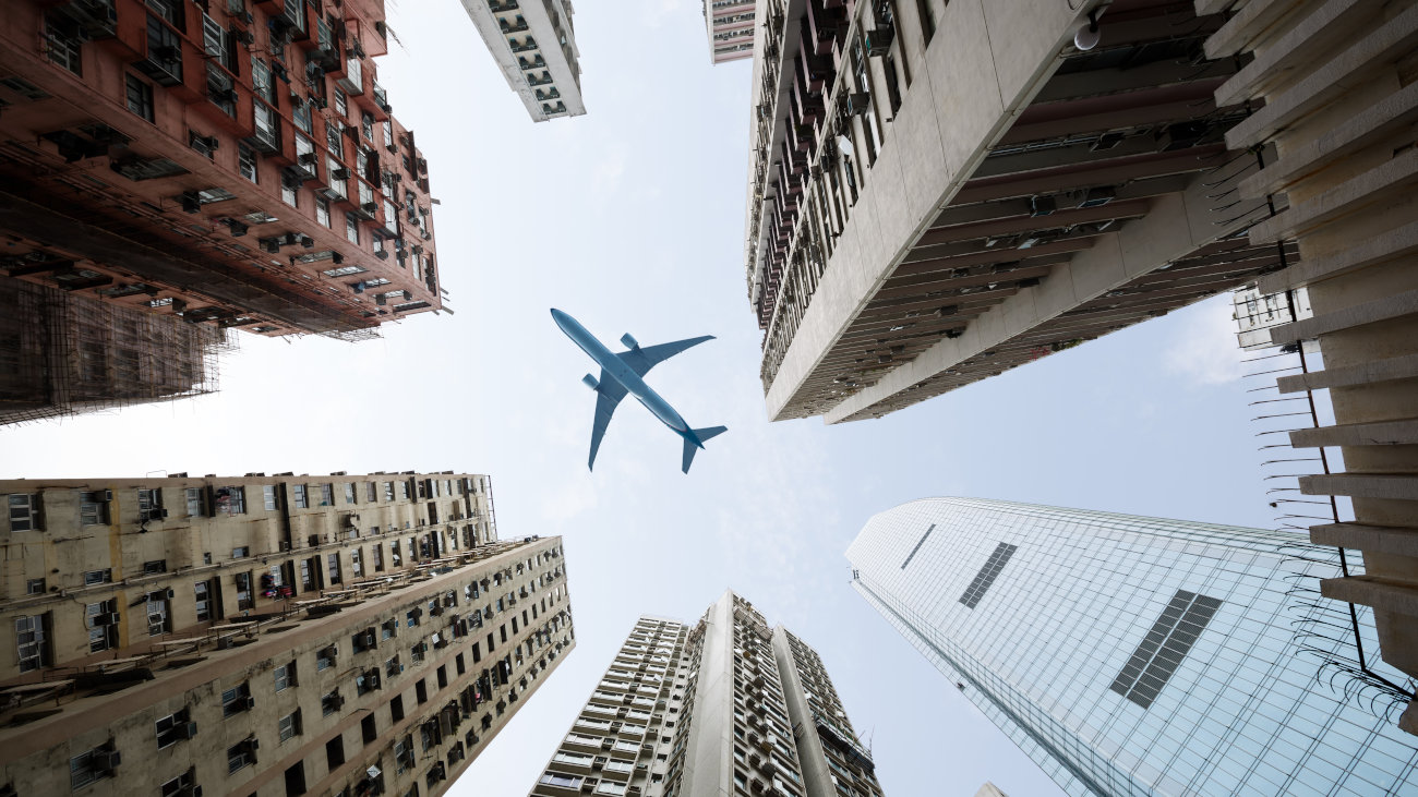 Looking up through skyscrapers and a passenger jet flying overhead.