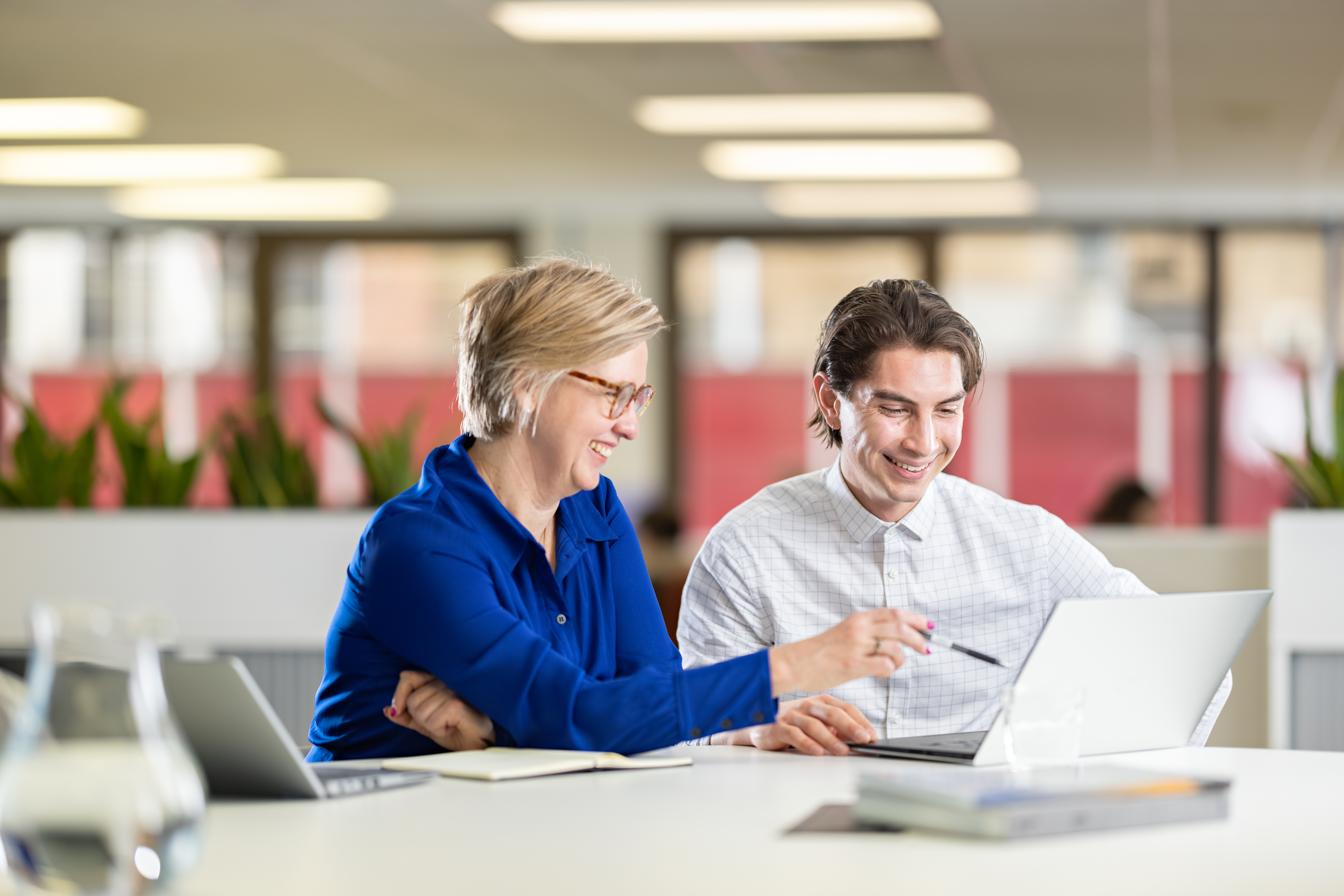 Two co-workers looking at a laptop.
