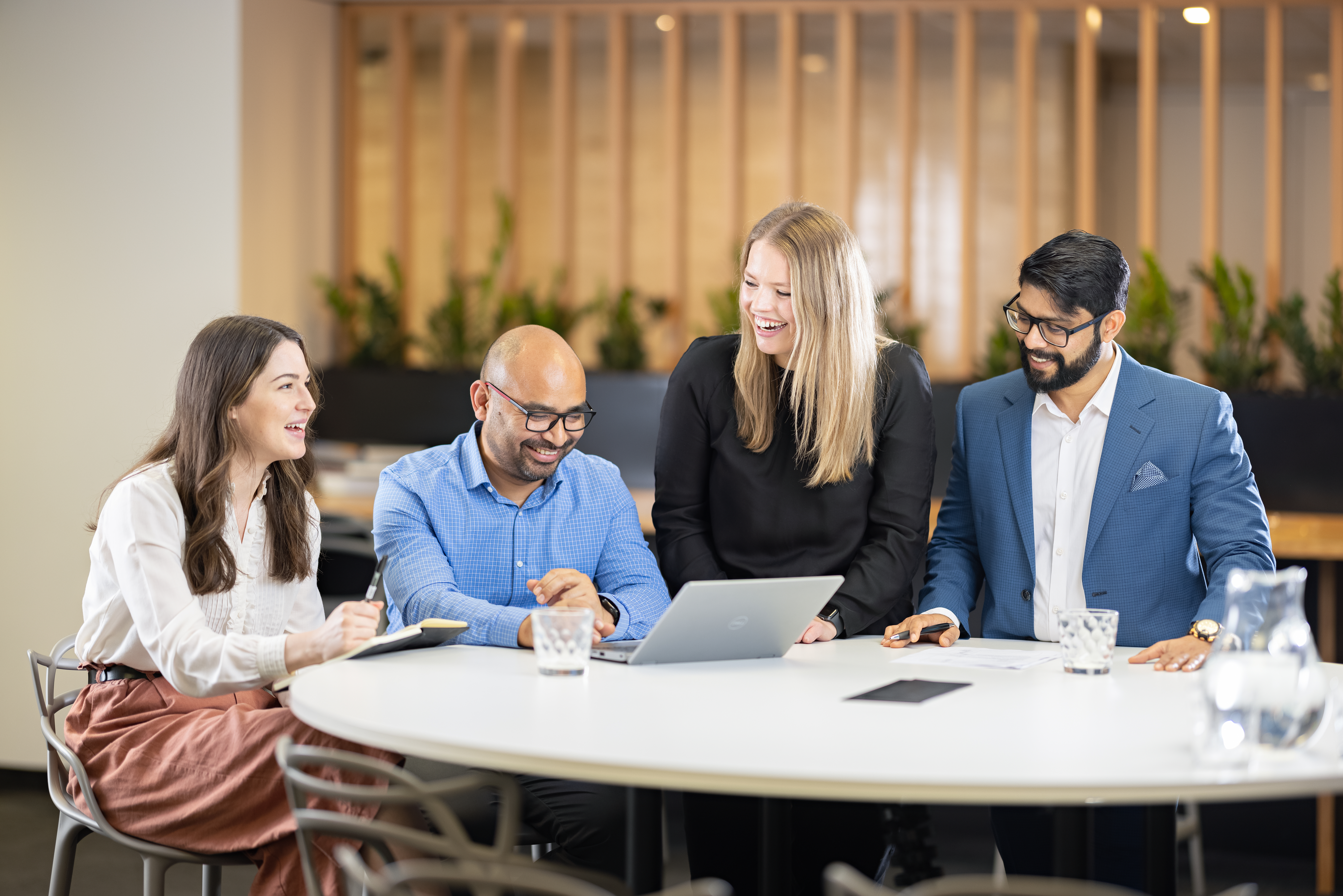 A group of workers gathered around a table in an office space. 
