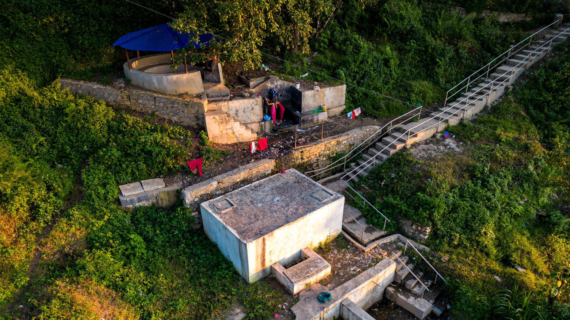 Women collecting water from a natural stone tap.