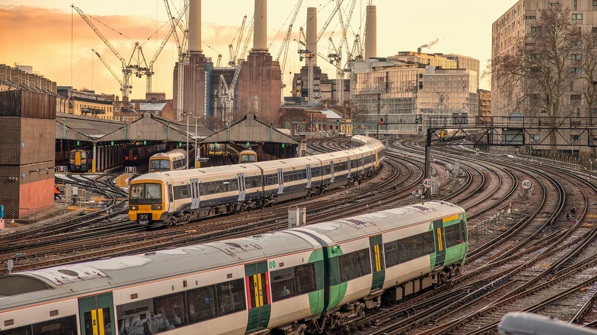 Multiple passenger trains moving through a complex rail junction in London, illustrating track and train integration and the future of rail safety in Great Britain.
