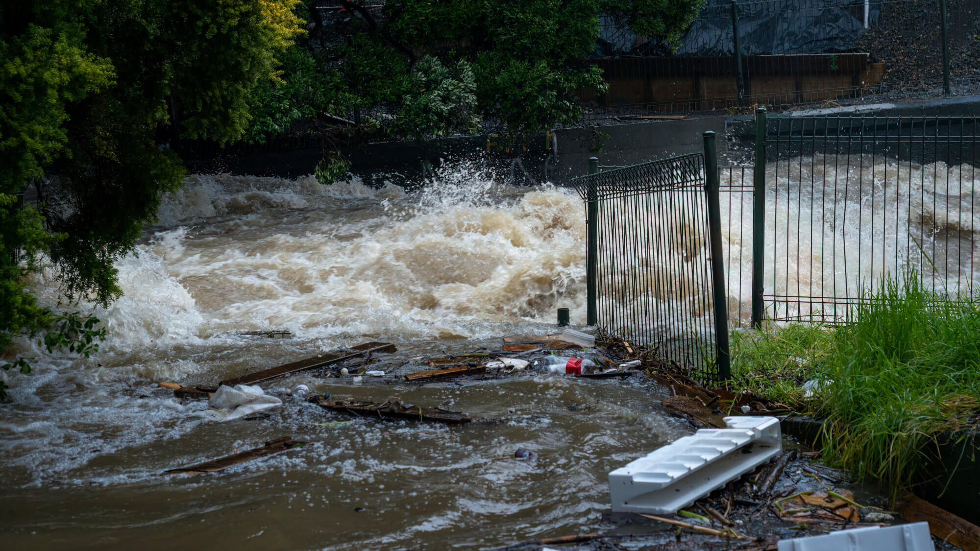 Rubbish floating on floodwater running down a street.