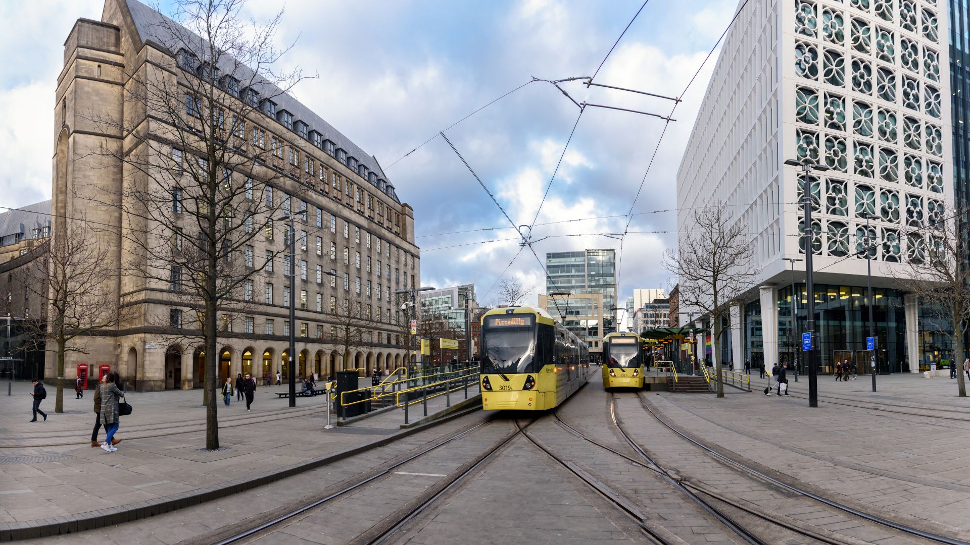 Manchester Metrolink trams at a central city stop, showing the integrated public transport network used as part of the region&rsquo;s place‑based approach to sustainable mobility.