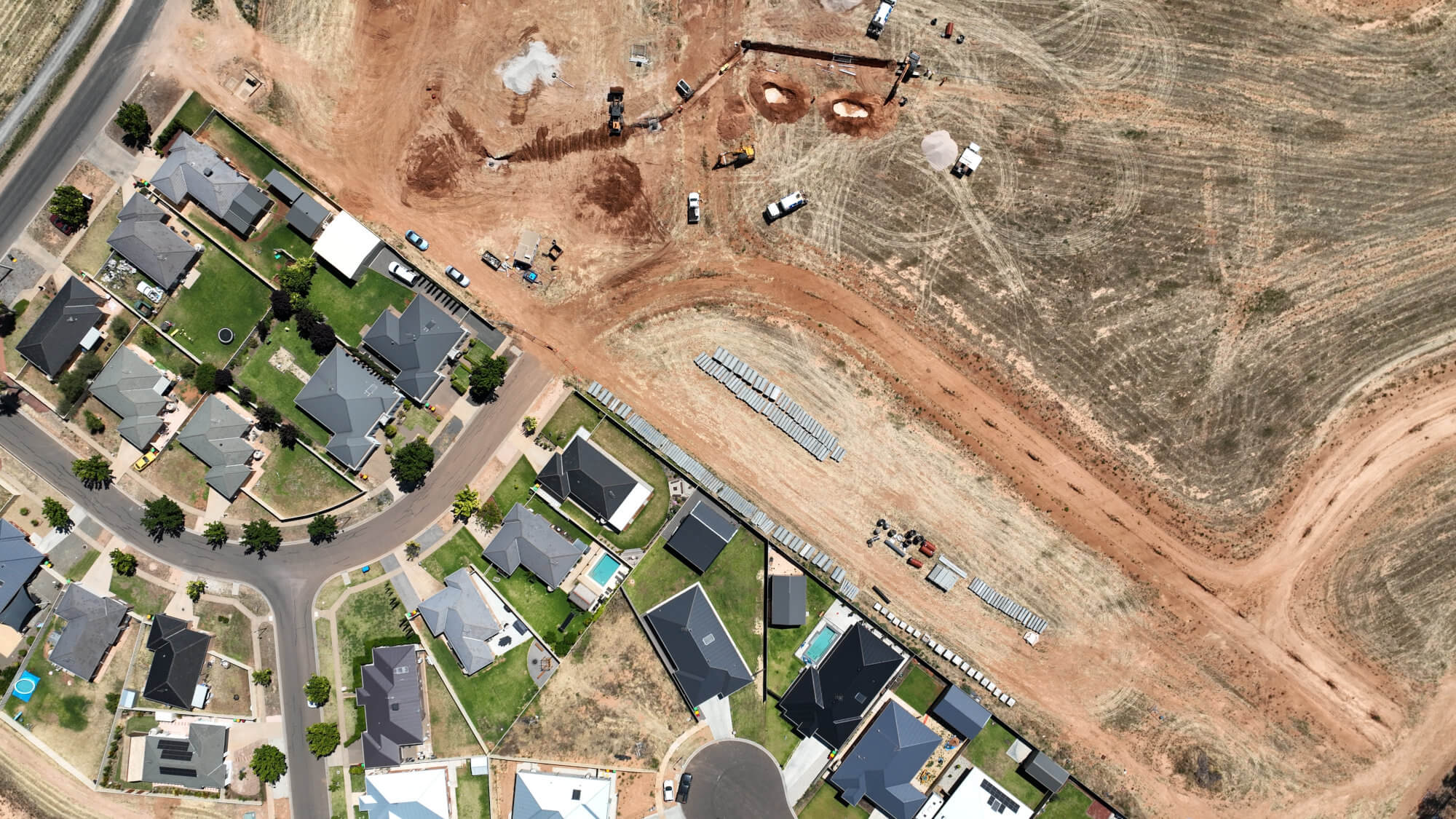 Aerial view of construction on the edge of a residential neighbourhood.