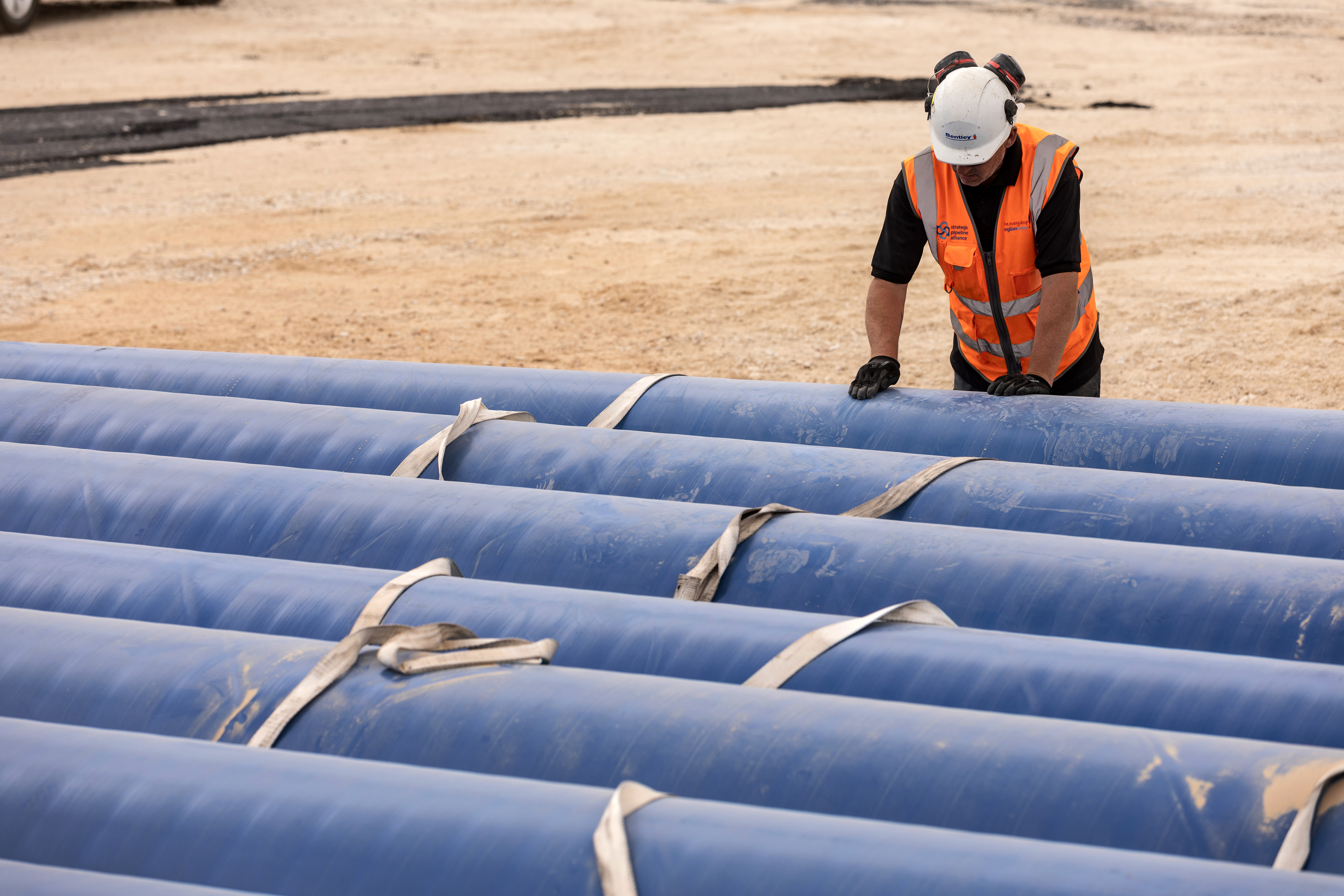 Construction worker standing in front of blue cylinders.